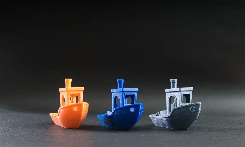 A variety of colorful 3D printer filament spools organized on a shelf